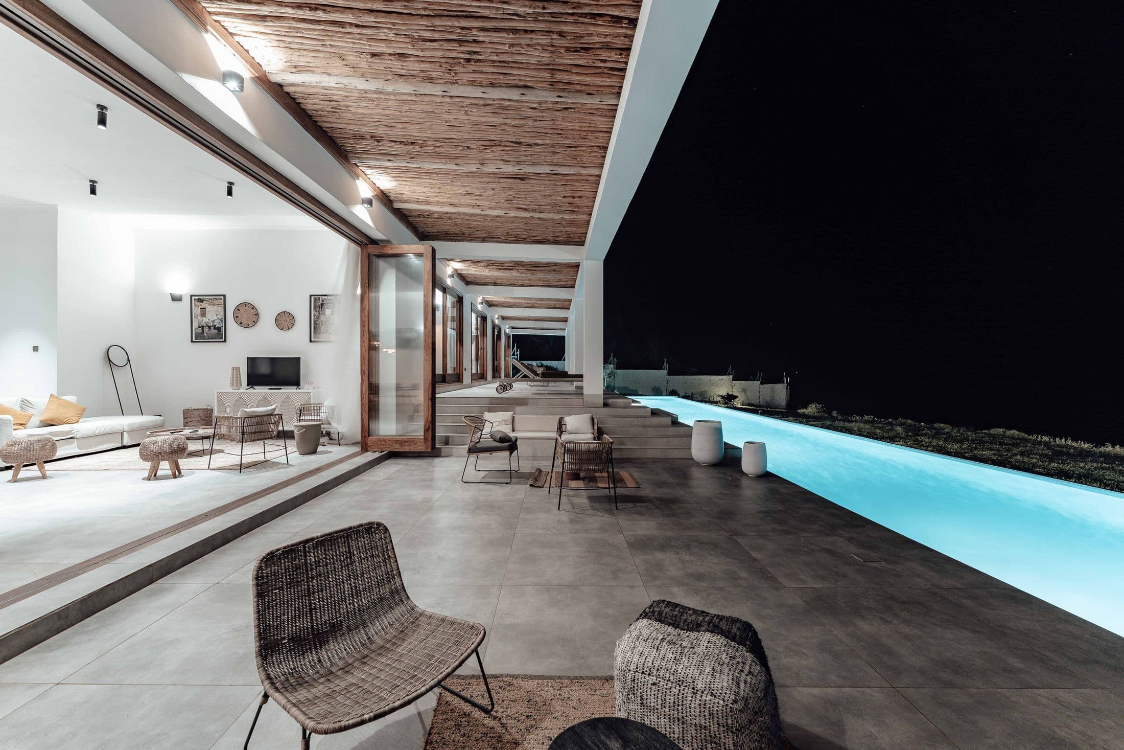 Open, light-filled living space opening onto a pool at evening